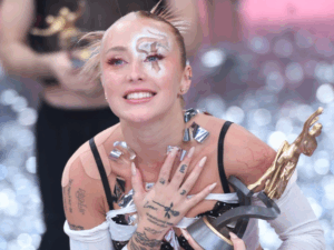 Tuli acosta con su premio por ganar el Bailando 2023, con pelo recogido, maquillaje y vestuario blanco